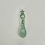 A small ceramic spoon or scoop with a star-shaped handle and a hole at the top, decorated with the name 'SAD' and a white circular mark near the bowl, shown on a plain light background.