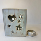 A ceramic heart-shaped candle holder with star cutouts, shown next to a matching small ring holder, both in a distressed light blue-gray glaze on a neutral background.