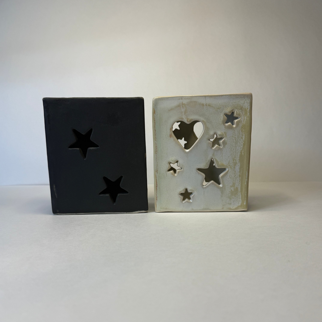 Two square ceramic decorative lanterns with star and heart cutouts, shown side by side on a white surface against a light gray background.