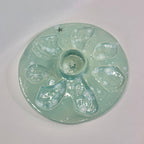 A round ceramic plate with a pale mint green glaze and five raised petal-like sections surrounding a central well, photographed on a plain light background.